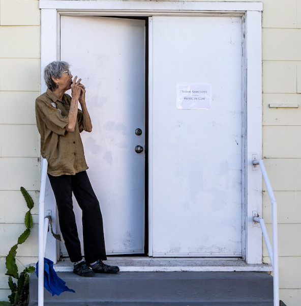 Artists Susan Rawcliffe playing one of her clay instruments on the porch of her studio.